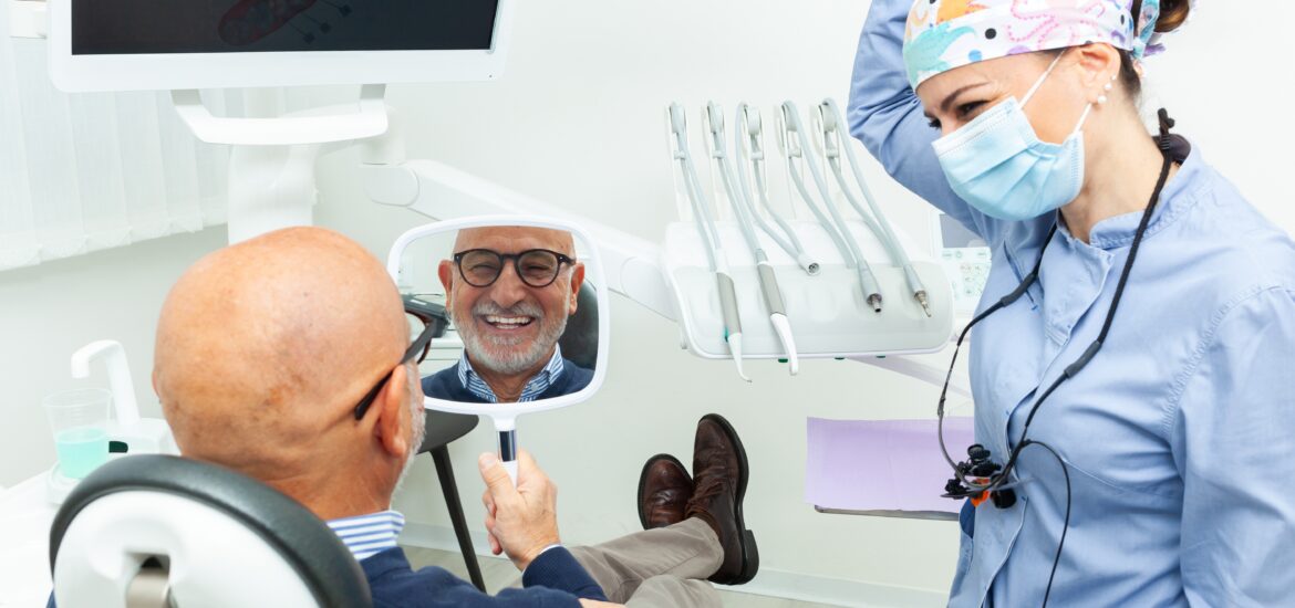 older man looking into mirror, happy with new dental implants