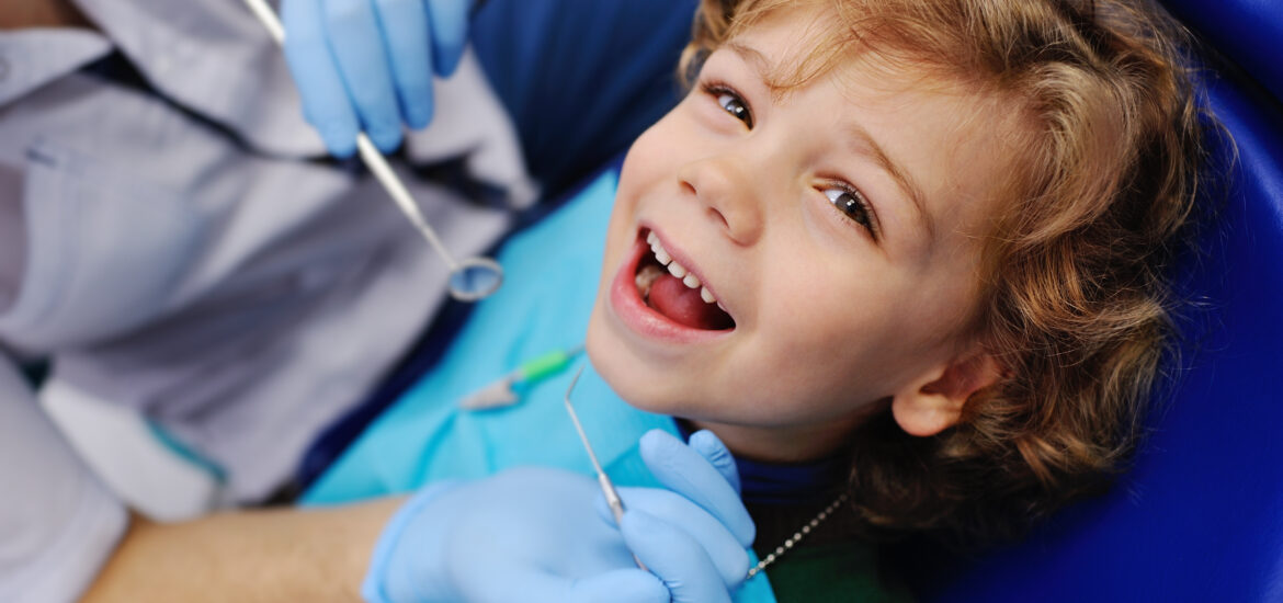 smiling child sitting in a blue dental chair
