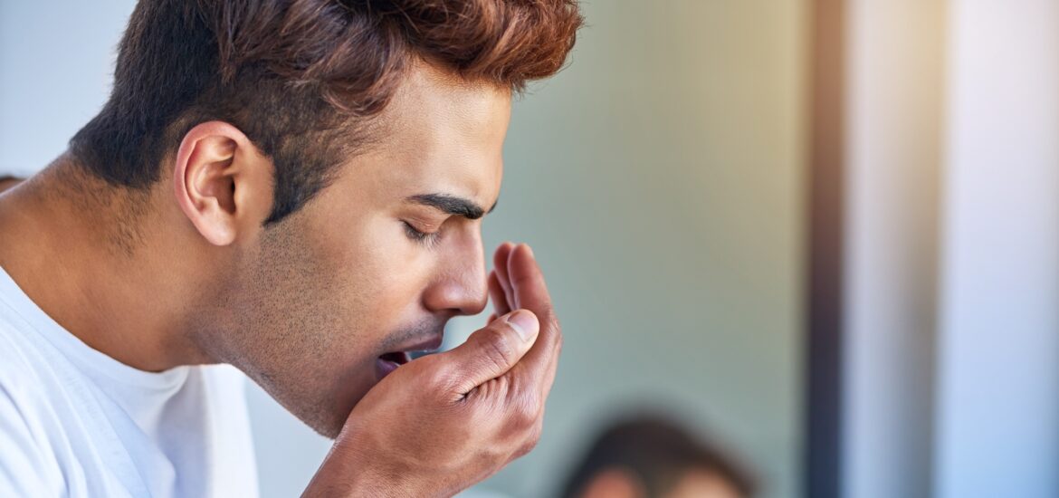 man blowing into his hand to check his breath, gum disease symptoms