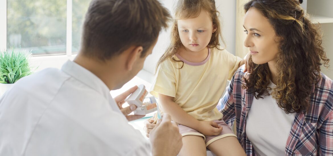 dentist advises the mother with her daughter about good oral health habits
