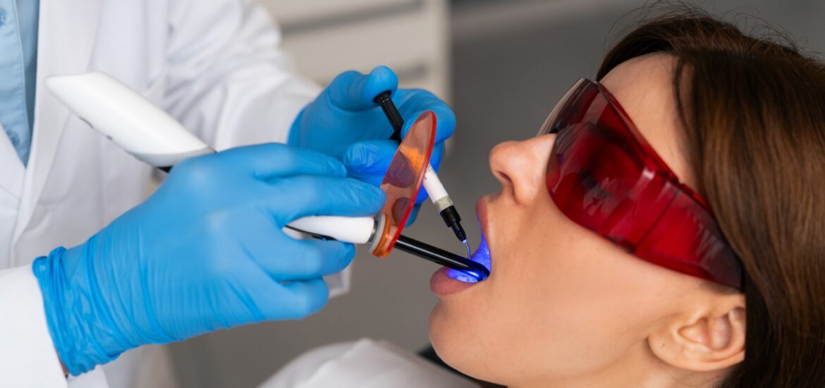 dentist in blue gloves using laser on female patient