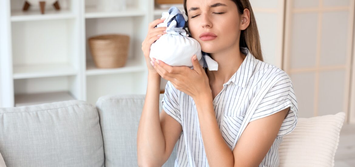 young woman sitting on couch icing her jaw, TMJ pain